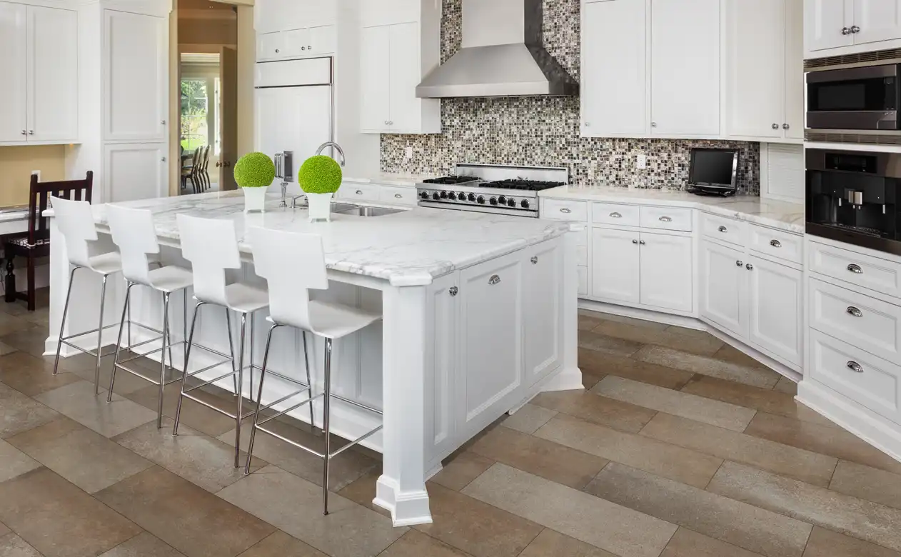 multi patterned mosaic backsplash tile in kitchen with white cabinets and marble countertop